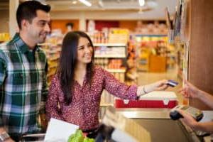 Young couple at grocery store checkout line paying with credit card